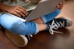 Jeans-Clad Teenager Scrolling Through Health Websites on Laptop to Find Health Advice Online | Vitacost/com/blog