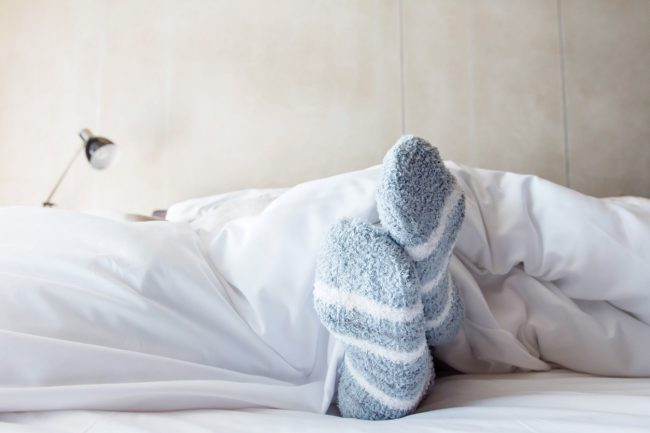 Blue Socks Under White Comforter Hide Crusty Feet While Also Helping to Heal Cracked Skin | Vitacost.com/blog