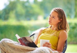 Woman Living With Endometriosis Relaxing With Book and Tea on Backyard Patio | Vitacost.com/blog