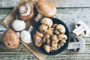 Concept of Mushroom Nutrition Demonstrated by Variety of Mushrooms Scattered on Wooden Table | Vitacost.com/blog