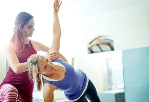 Woman Participating in Assisted Stretching Session With Personal Trainer at Gym | Vitacost.com/blog