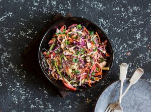 Colorful coleslaw recipe with seeds in a black bowl