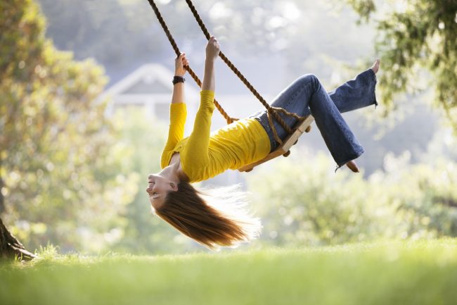 An Adult Woman in Yellow Shirt & Jeans Enjoys Swinging Like a Kid for Her Health | Vitacost.com/blog