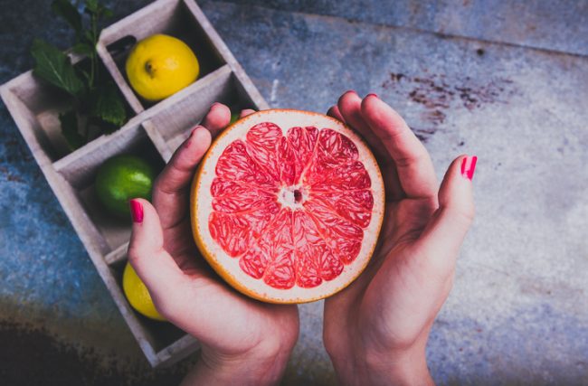 Polished Hands of Woman Considering Becoming Vegan to Reduce Carbon Footprint Holding Ruby Red Grapefruit | Vitacost.com/blog