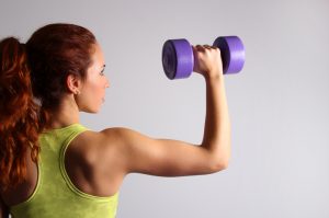 Back View of Ponytailed Woman Holding Purple Dumbbell Learning How to Build Muscle | Vitacost.com/blog