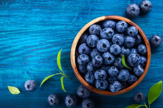 Bowl Filled With Blueberries on Blue Wooden Table Representing Superfoods Easily Grown at Home | Vitacost.com/blog