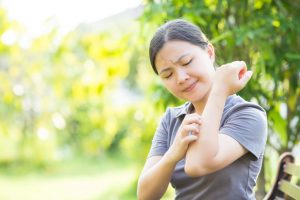 Woman Itching Arm in Park Who Needs Natural Remedies for Bug Bites | Vitacost.com/blog