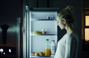 Woman Standing in Front of Refrigerator Contemplating Eating Before Bed | Vitacost.com/blog