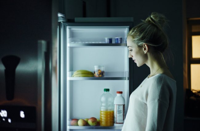 Woman Standing in Front of Refrigerator Contemplating Eating Before Bed | Vitacost.com/blog