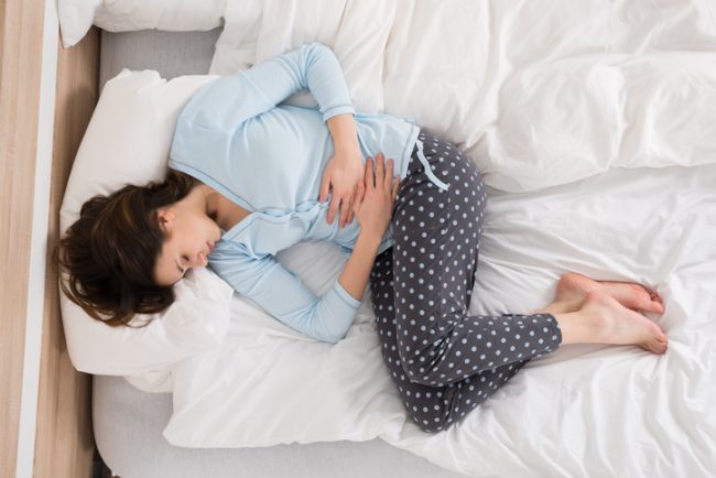 Vacationing Woman in Bed Suffering from Irritable Bowel Syndrome | Vitacost.com/blog