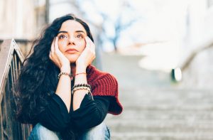 Confused-Looking Woman Struggling with Brain Fog Staring at Nothing While Sitting in Stairwell | Vitacost.com/blog