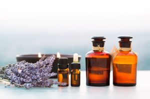 Amber Bottles of Essential Oils for Women's Health Lined Up on White Table with Candle | Vitacost.com/blog