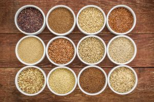 Twelve White Bowls Filled With Variety of Whole Grain Foods on Wooden Surface | Vitacost.com/blog
