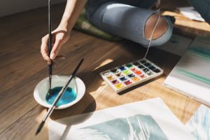 Woman Practicing Art Therapy Techniques Sitting on Floor with Paint, Brushes and Canvas | Vitacost.com/blog