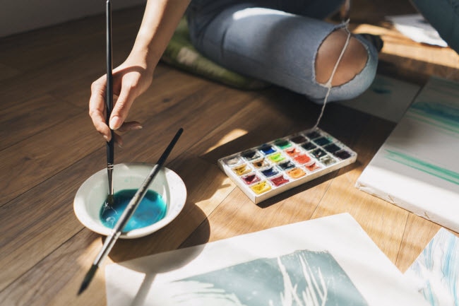 Woman Practicing Art Therapy Techniques Sitting on Floor with Paint, Brushes and Canvas | Vitacost.com/blog