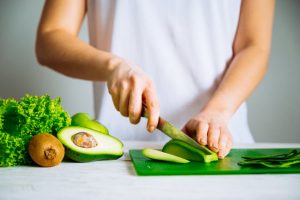 Person Concerned About Signs of Ketosis Slicing Keto-Diet-Friendly Avocado on Cutting Board | Vitacost.com/blog