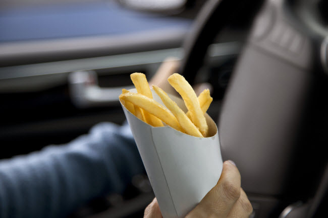 Person Holding Carton of Greasy Food French Fries While Driving Car | Vitacost.com/blog