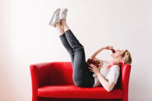 What is Comfort Food Question Answered by Woman Lying on Red Couch Ecstatically Eating Strawberries | Vitacost.com/blog
