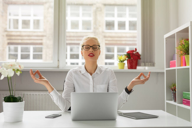 Women Meditating at Desk in Positive Office Environment to Represent Workplace Health | Vitacost Blog 