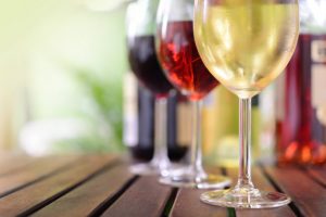 Row of Filled Wine Glasses on Wooden Bar to Represent Need to Quit Drinking Alcohol | Vitacost.com/blog