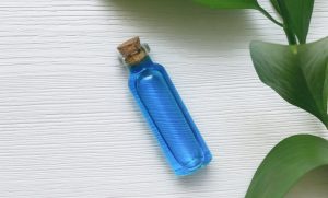 Bottle of Skincare Trend Blue Tansy Oil on White Wooden Surface with Green Leaves | Vitacost Blog