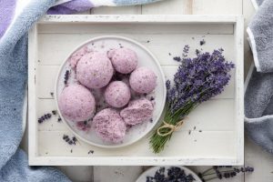 Purple Homemade Bath Bombs Made With Coconut Oil on White Wooden Tray with Lavender Flowers | Vitacost.com/blog