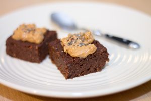 Two Brownies Topped with Sunflower Butter on Plate Next to Spoon | Vitacost Blog