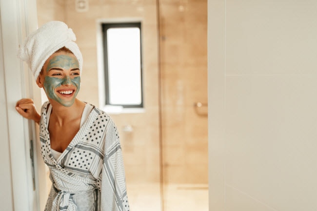 Young Woman With Towel on Head and Green Cream on Face Trying Home Remedies for Acne | Vitacost.com/blog