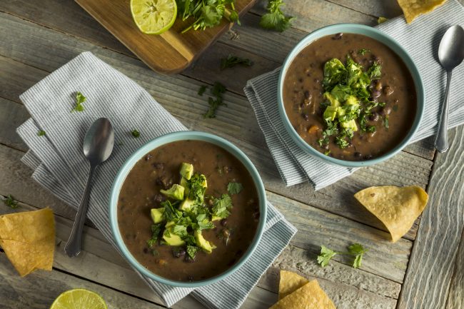 Simple Black Bean Soup Two Bowls of Black Bean Soup Topped with Avocado | Vitacost Blog