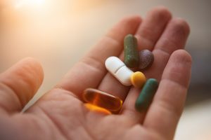 Hand Holding Vegan Vitamins and Supplements | Vitacost.com/Blog