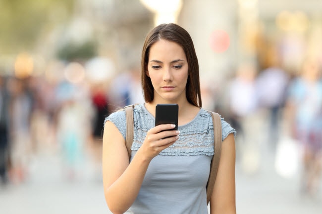 Dazed Woman Staring at Phone Suffering Some Negative Effects of Social Media on Mental Health | Vitacost.com/blog
