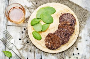 Black Bean Burger Patties on Round Tray Next to Spinach Leaves | Vitacost Blog
