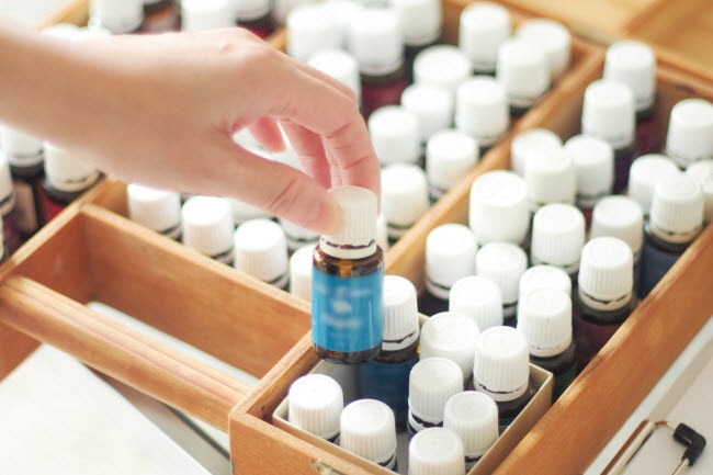 Woman Learning How to Use Essential Oil Selecting Bottle from Drawer Filled With Products | Vitacost.com/blog