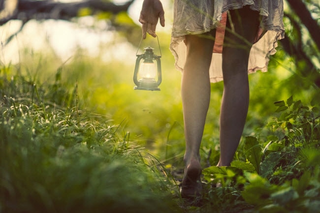 Woman Walking Barefoot in the Woods with Lantern to Reduce Anxiety with Grounding Technique | Vitacost.com/blog