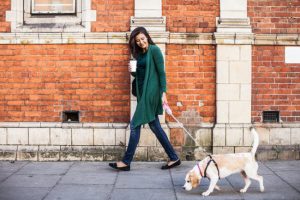 Woman Who Figured Out How to Exercise Despite Busy Schedule Walking Dog Down City Street | Vitacost.com/blog