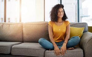 Woman Contemplating Mental Health Screening While Sitting On Couch | Vitacost.com/blog