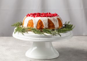 Festive Orange-Pomegranate Bundt Cake on White Stand with Fresh Greenery | Vitacost.com/blog