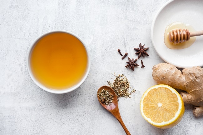 7 Winter Herbs for Health & Wellness Overhead View of Winter Herbs and Lemon to Make Tea on White Marble Surface | Vitacost.com/blog