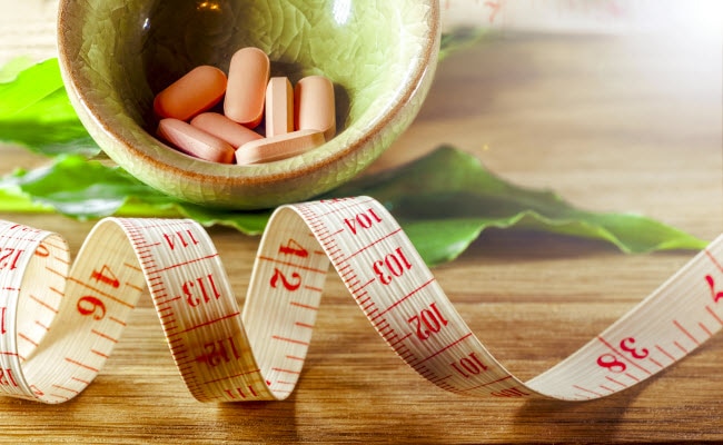 Concept of Diet Tips Represented by Measuring Tape and Bowl of Supplements on Wooden Table | Vitacost.com/blog