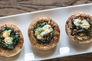 Row of Stuffed Portobello Mushrooms on White Plate on Wooden Table | Vitacost.com/blog
