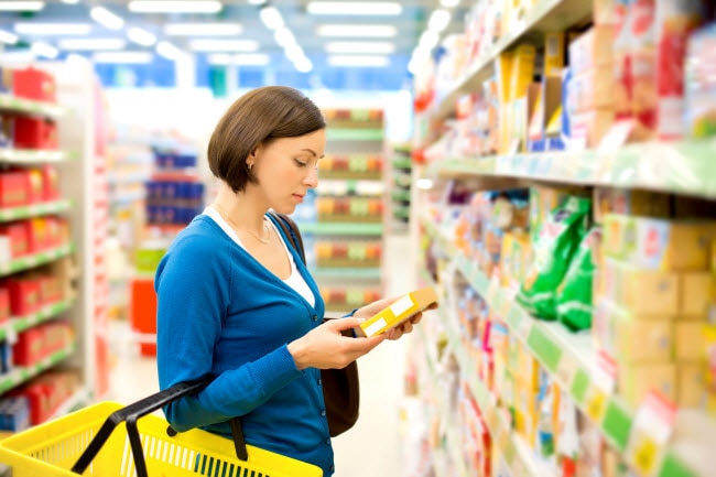 Glyphosate: Get the Facts About This Controversial Chemical Woman Wondering What is Glyphosate Examining Label of Cracker Box in Grocery Store Aisle | Vitacost.com/blog