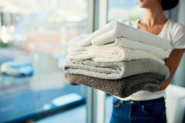 Woman Holding Folded Towels After Eco-Friendly Laundry Routine | Vitacost.com/Blog