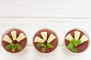 Row of Three Healthy Chocolate Pudding Desserts with Pineapple and Mint Topping on White Wood Table | Vitacost.com/blog