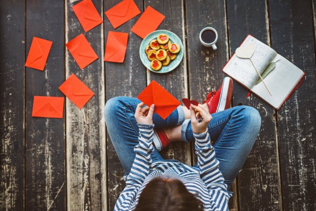 3 Romantic Ideas for Saying "I Love You"  Jeans-Clad Woman Executing Romantic Ideas by Writing Love Letters to Say I Love You to Her Valentine | Vitacost.com/blog