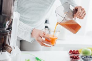 Woman Following Detox Tips Pouring Fresh Fruit Smoothie From Pitcher Into Glass | Vitacost.com/blog