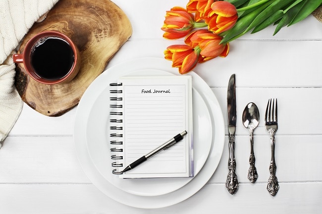 Does Calorie Counting Work for Weight Loss Exemplified by Food Journal at Place Setting on White Table | Vitacost.com/blog