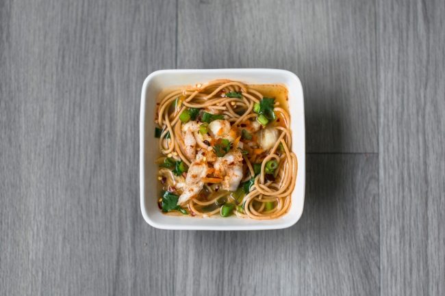 Kimchi and Chickpea-Noodle Soup (Vegan & Gluten-Free) Top View of Square White Bowl of Kimchi Soup on Gray Wood | Vitacost Blog