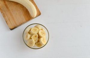 Potassium Health Benefits Represented by Bowl of Sliced Bananas and Whole Banana on Wooden Cutting Board | Vitacost.com/blog