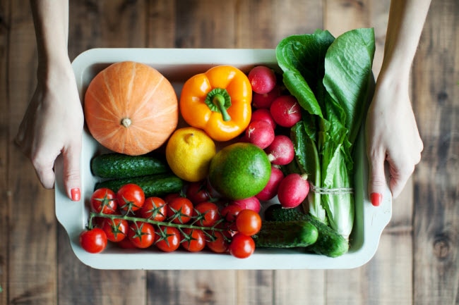 Woman Holding White Roasting Pan Full of Colorful Vegetables to Represent What are Functional Foods | Vitacost.com/blog
