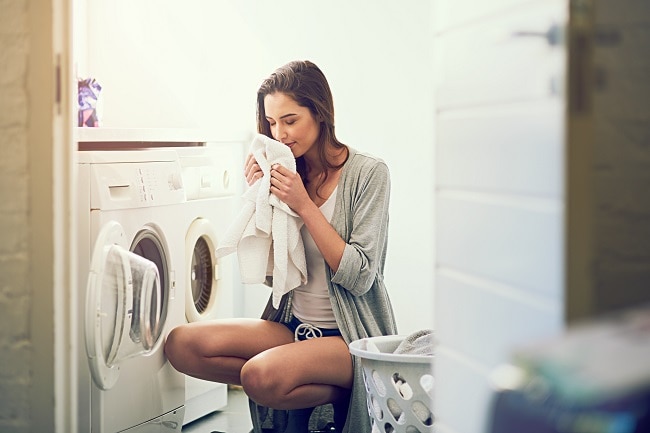 Woman Admiring Laundry Fresh From the Dryer After Using Safe Fabric Softener | Vitacost.com/Blog